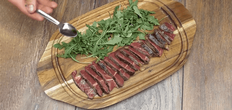 Faux filet sur os façon Tagliata sur une planche en bois accompagné de salade